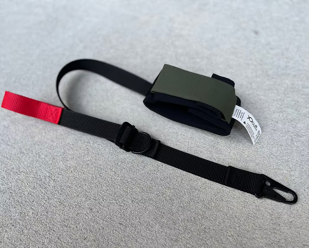 Black XDcuff REF115C strap with red buckle on a gray surface