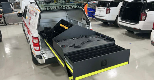 Rear bed slide storage system for emergency response trucks, featuring a drawer and storage unit for organized and accessible equipment storage.