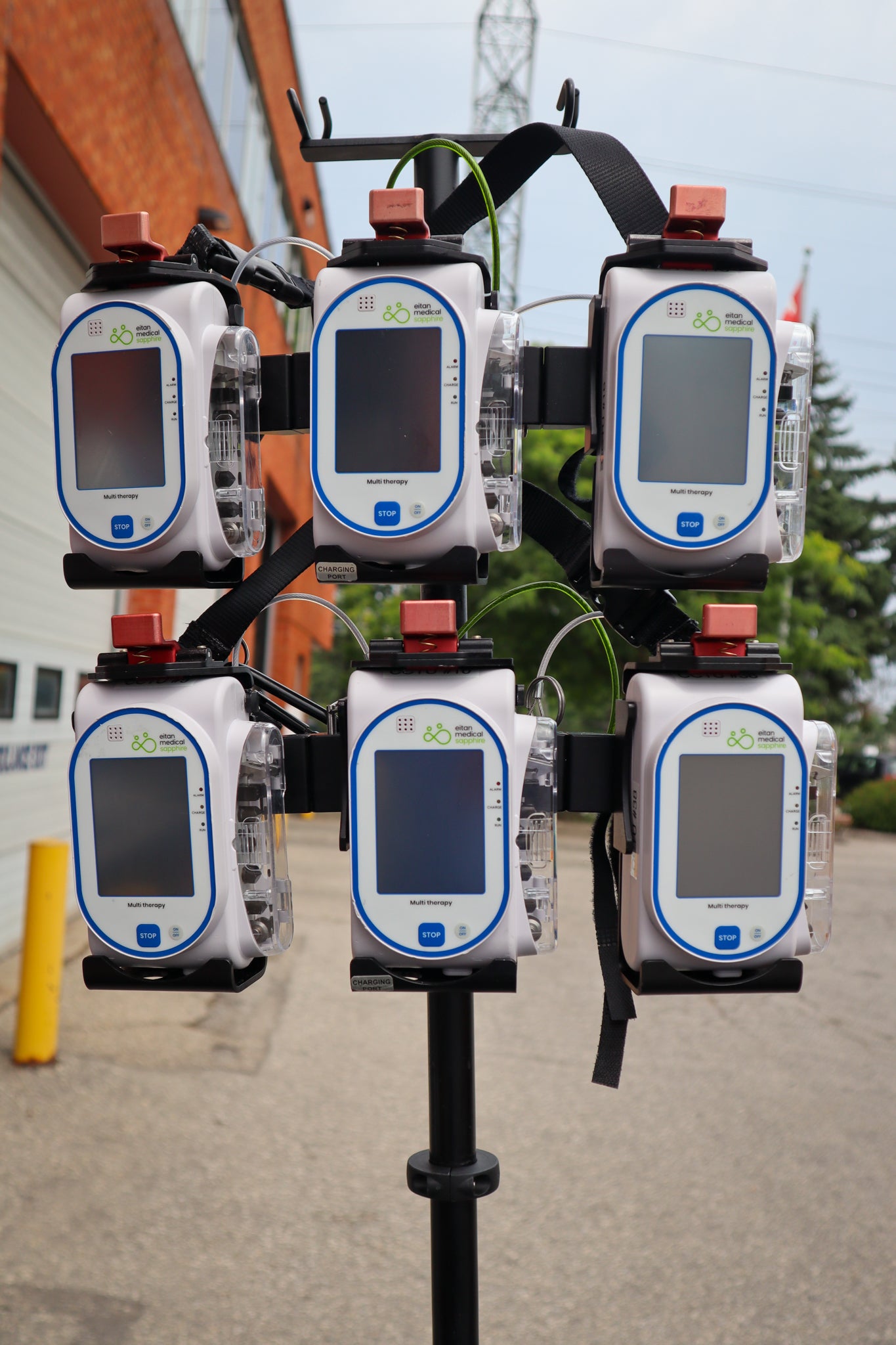 Multiple Sapphire pumps on a Rowland Emergency critical care pole, outdoors in a parking lot.