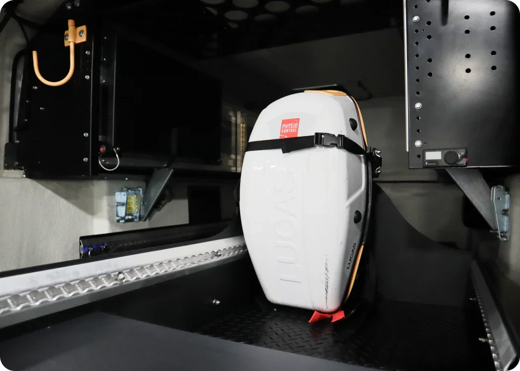 Stryker LUCAS II mounting bracket with Stryker LUCAS II securely mounted and strapped in the rear cargo storage area of an emergency response vehicle, ensuring safe and organized equipment storage.