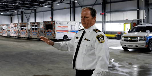 Paramedic chief in uniform stands in ambulance bay with Peel Regional Paramedic Services vehicles.