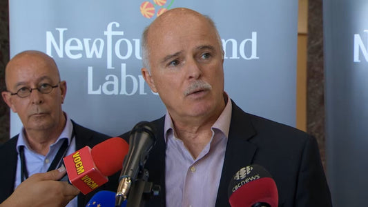 Man speaking at Newfoundland and Labrador press event with microphones, emergency service topic