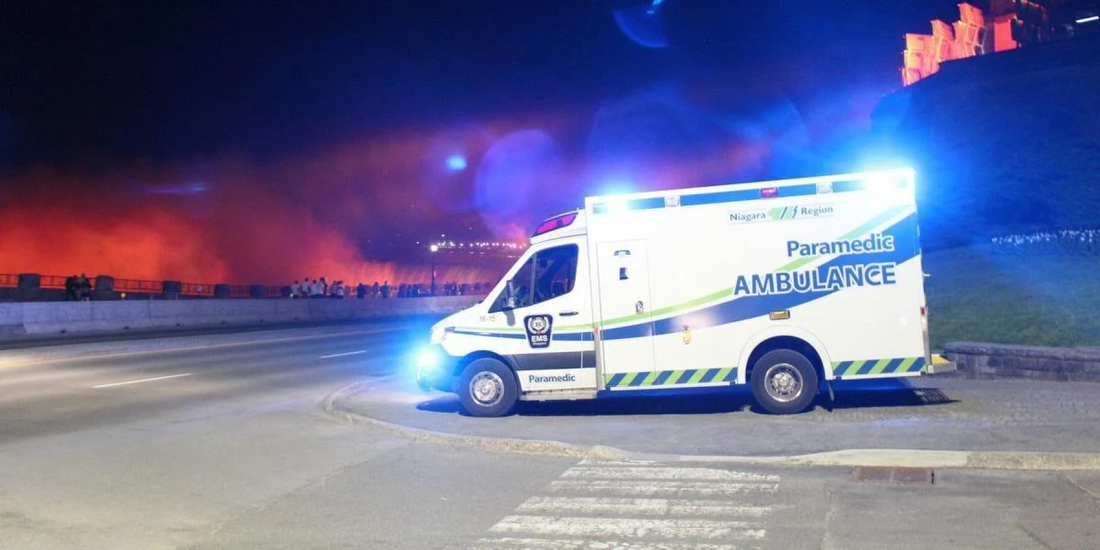 Niagara Region paramedic ambulance with emergency lights at night, near smoky orange-lit area