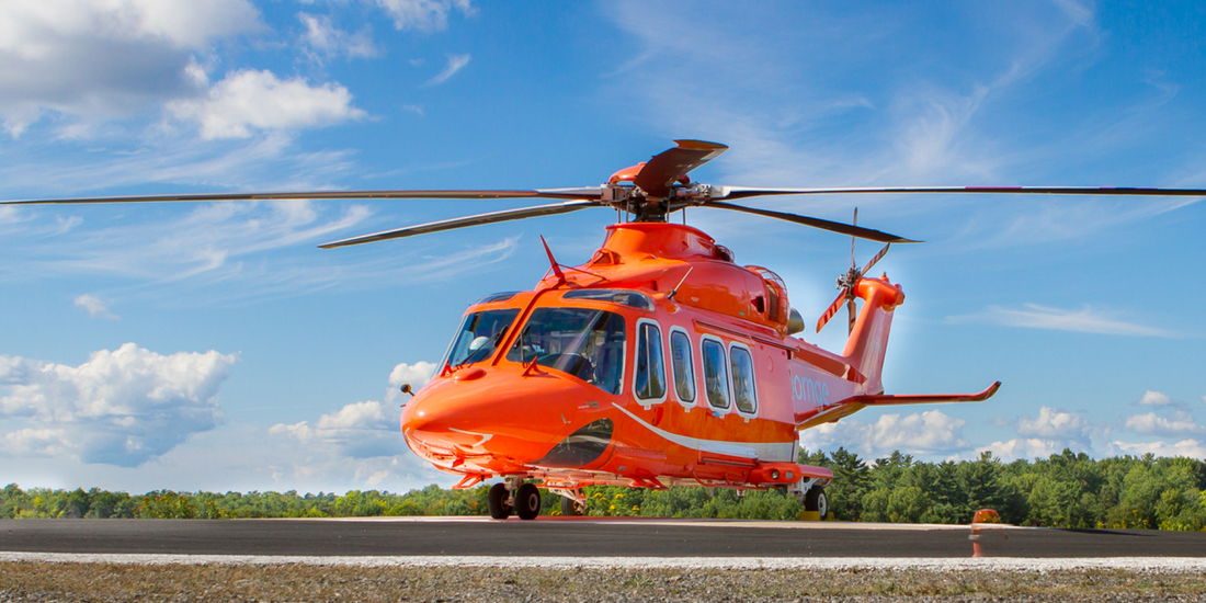 Bright orange Ornge air ambulance helicopter on helipad under blue sky, Rowland Emergency