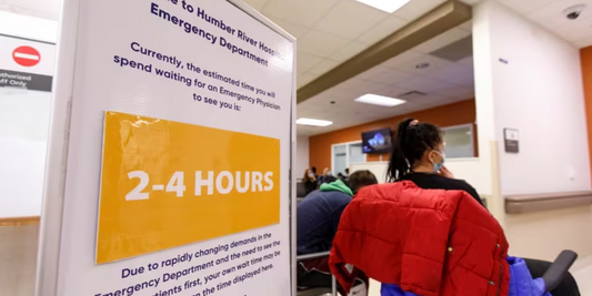 Emergency room waiting area with sign showing 2-4 hour wait, people seated, Rowland Emergency context