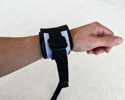 Hand wearing a black XDcuff REF117 disposable wrist support strap on a light gray background