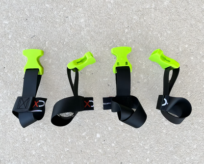Four XDcuff REF115 black straps with green ends on a concrete surface