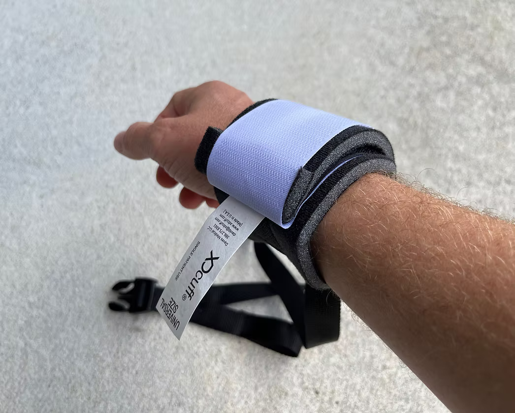 Hand wearing an XDcuff REF117C strap with a visible brand tag on a light gray background