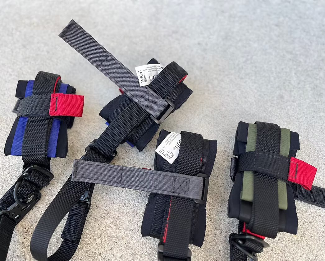 Set of XDcuff REF115C+ black straps with red and blue accents on a textured surface