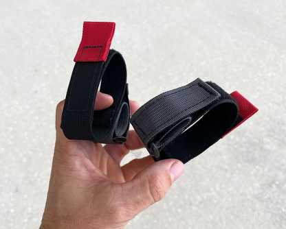 XDcuff REF105 black straps with red ends held by a hand against a neutral background