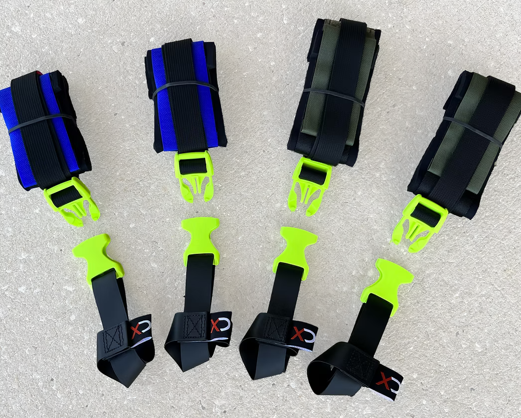 Set of XDcuff REF115 black and green straps with quick-release clamps on a concrete surface