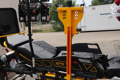 EMT stretcher and Rowland Emergency critical care products with XPS branding on a vehicle, with an Emergency Services truck in the background.